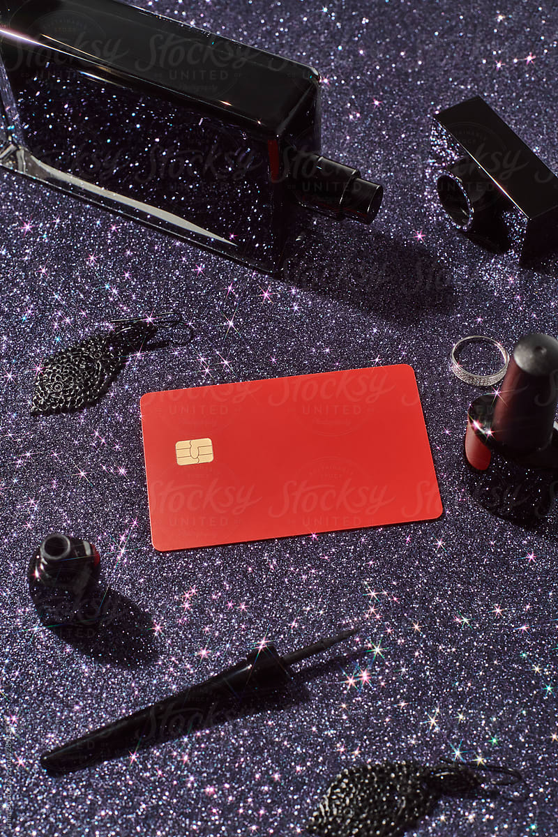 Credit card surrounded by cosmetics and jewelry.