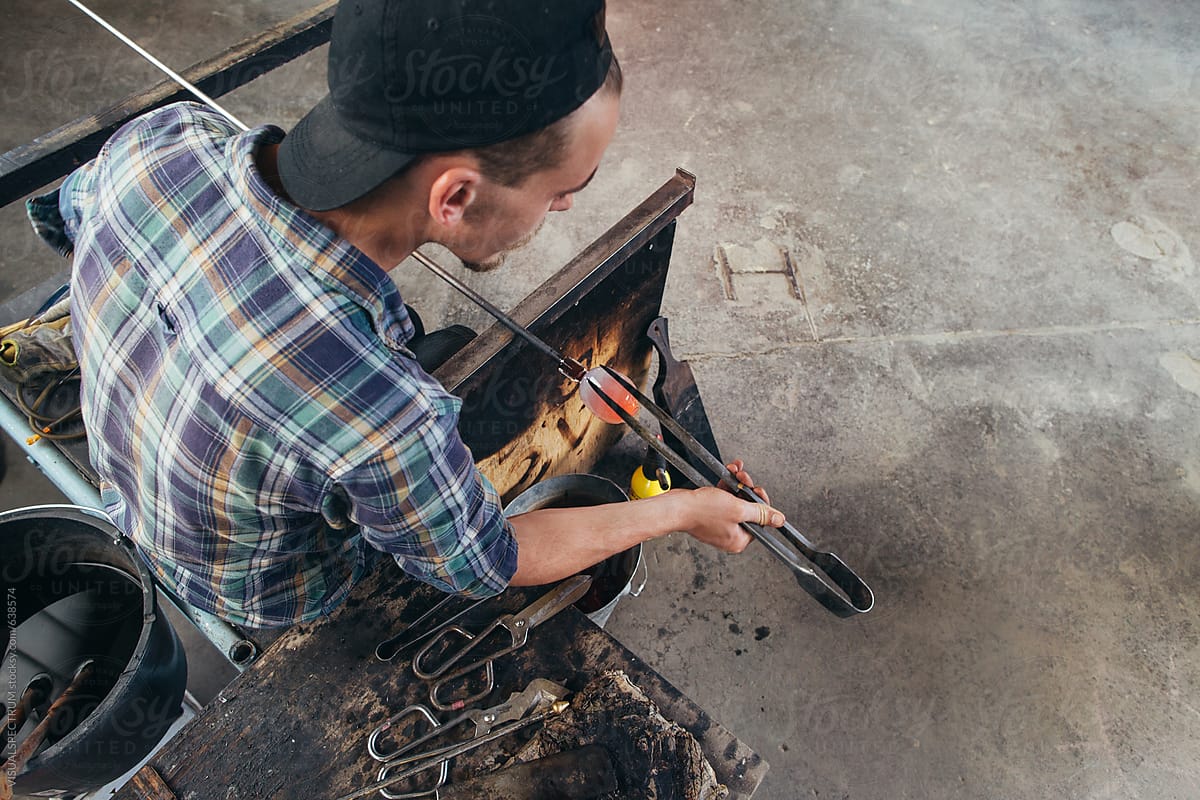 Artisan Glass Workshop - Overhead Shot of Male Hipster Artist Shaping Hot Glass With Jacks