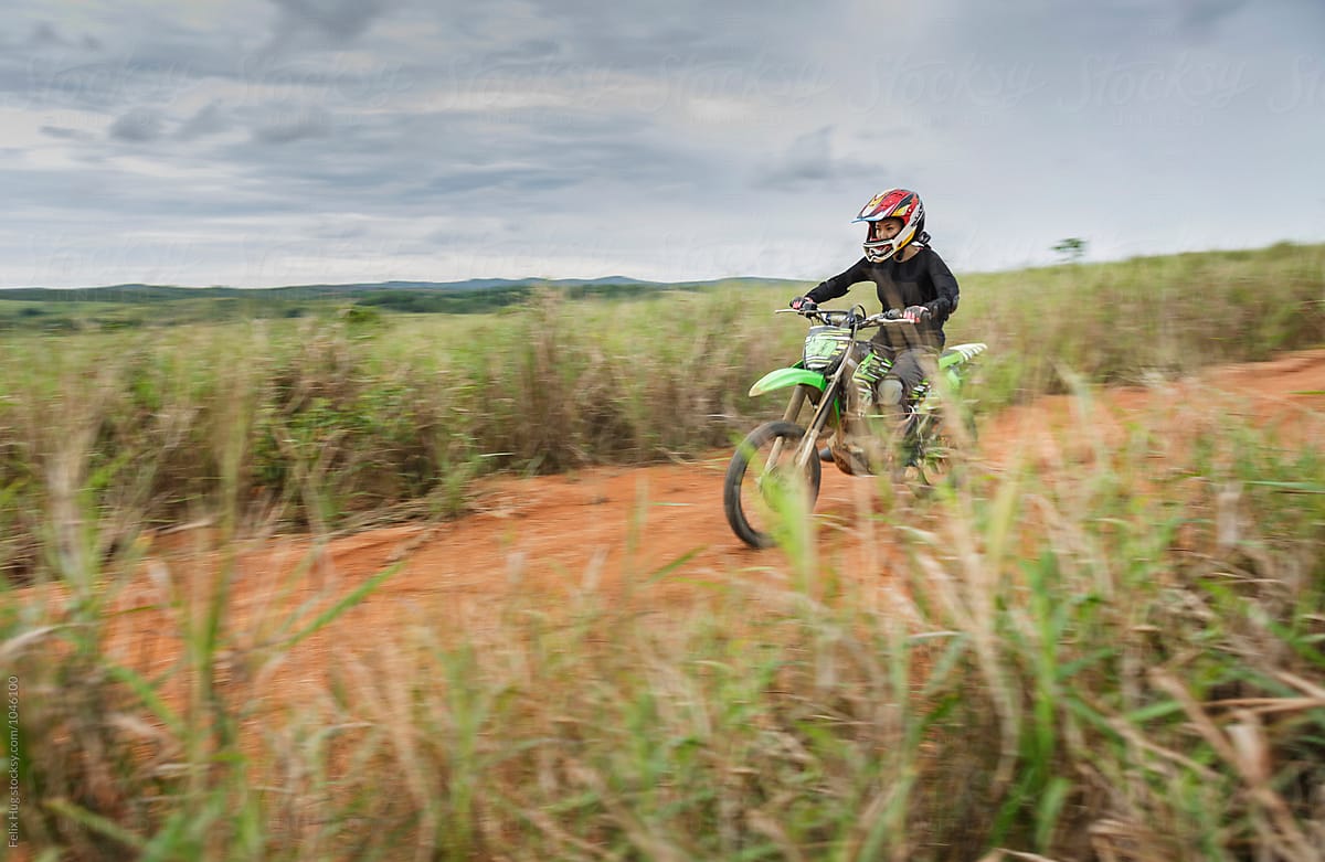 An asian woman is racing through a rural landscape on her motocross bike