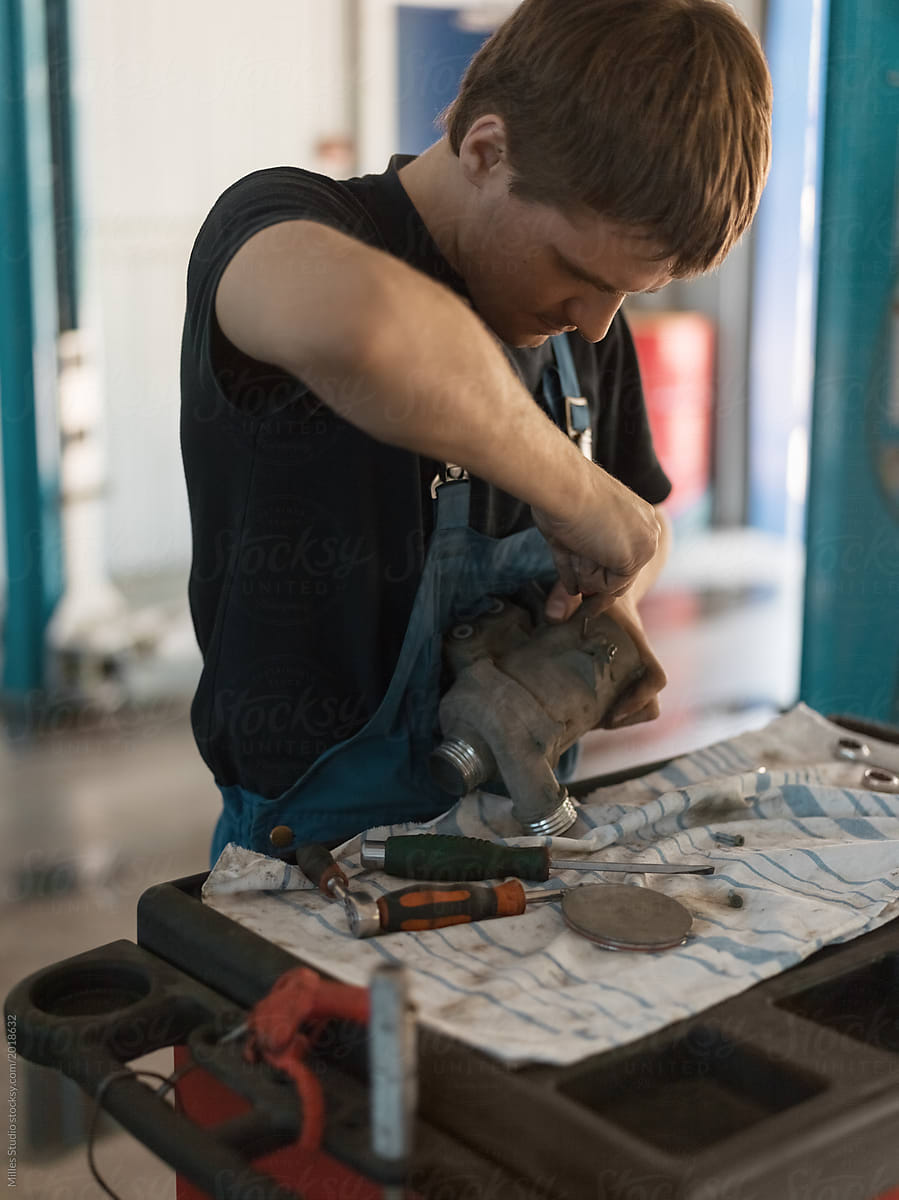 Mechanic in car shop fixing detail