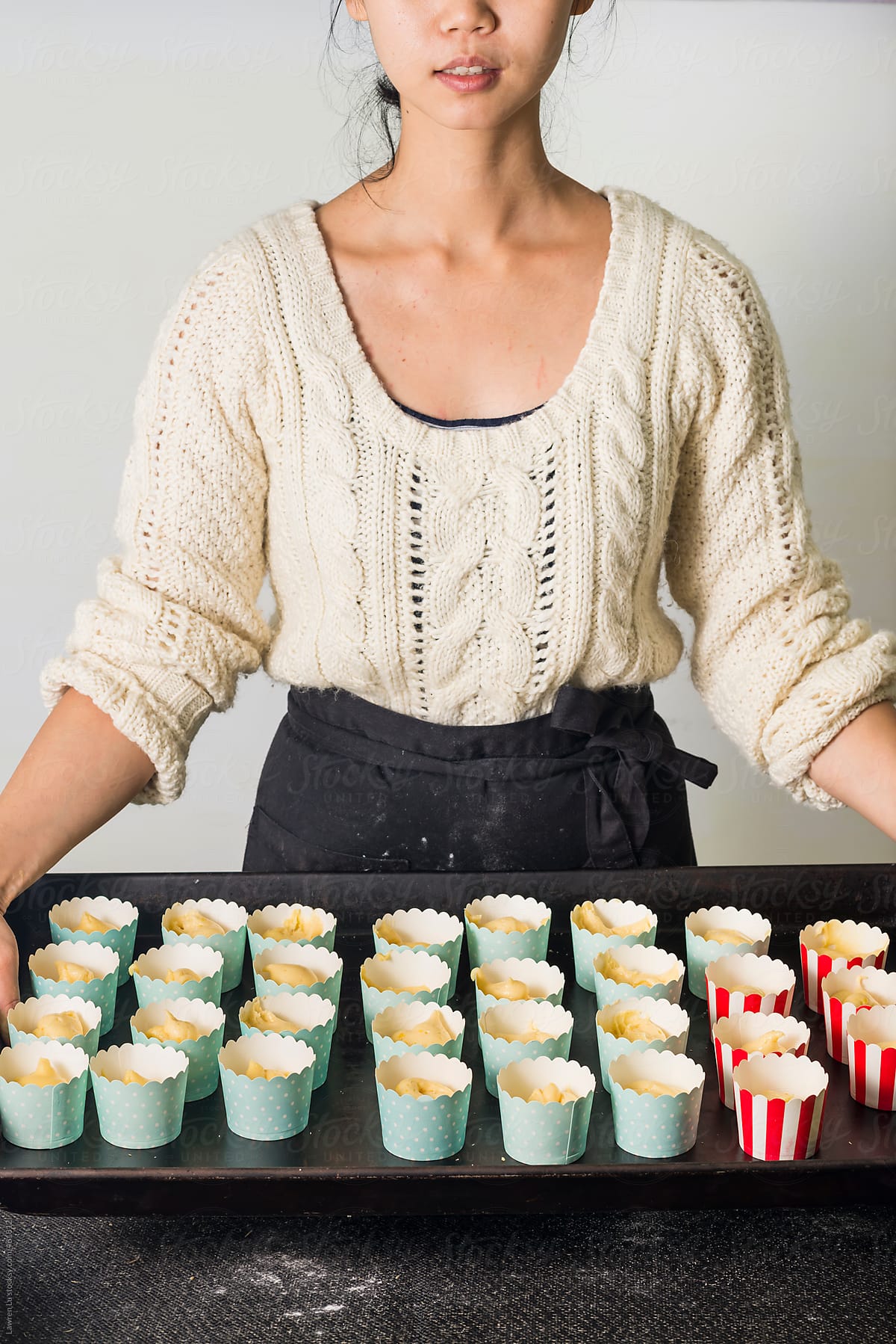 Young woman holding a tray of muffin cake batter- ready for baking.