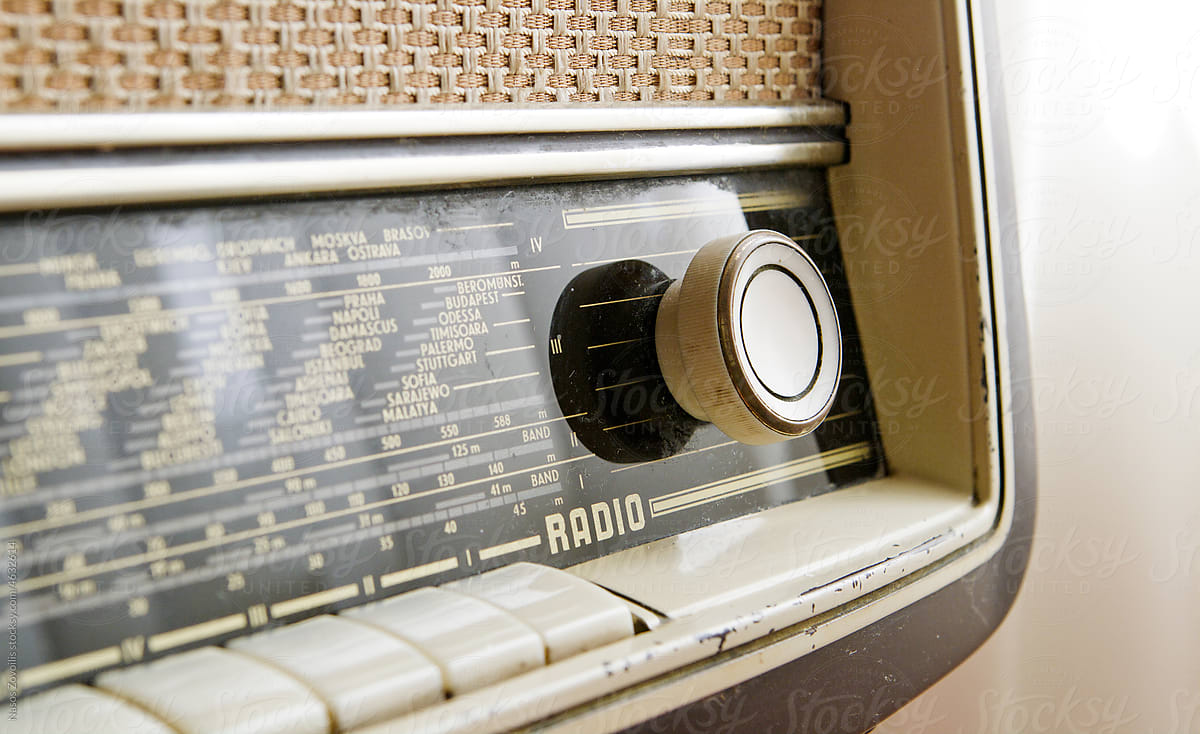 Close up of man hands adjusting frequency on vintage radio with knob
