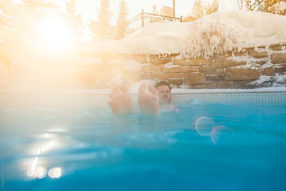 Man Relaxing In Outdoor Pool Spa In Winter at Ski Resort