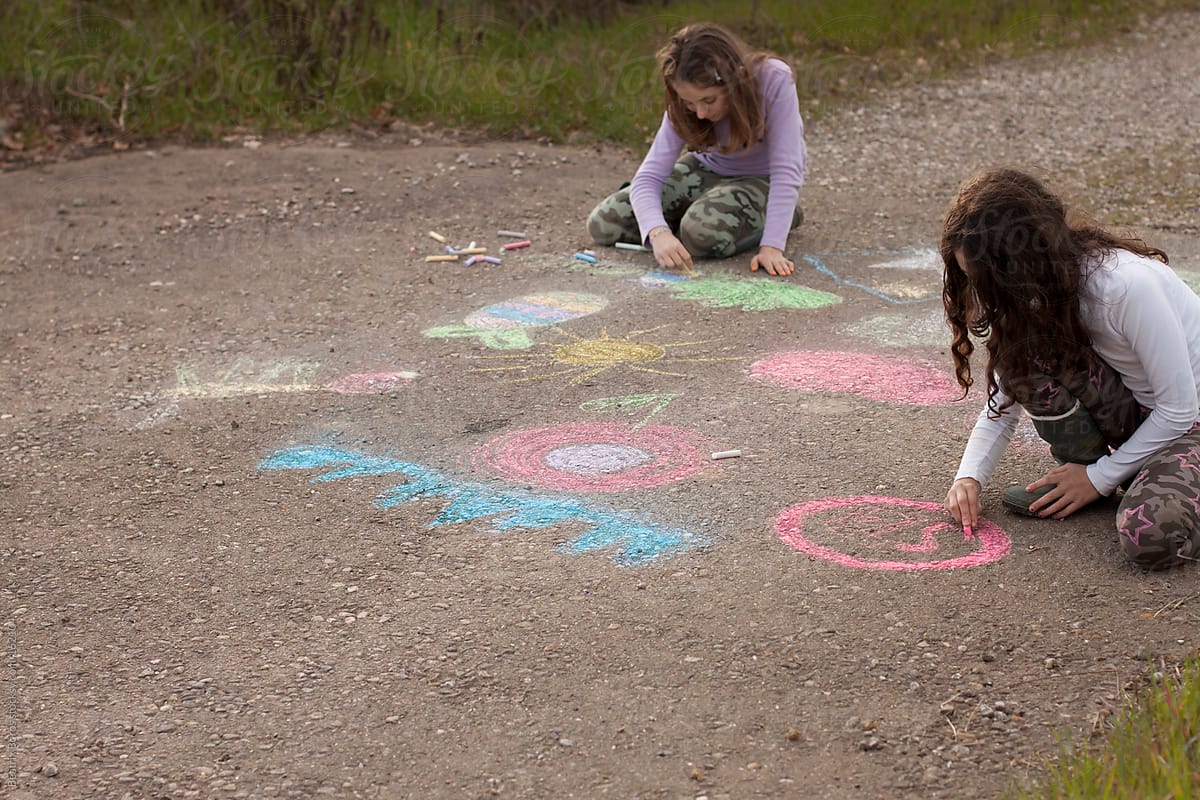 Two girls drawing with chalk on the road