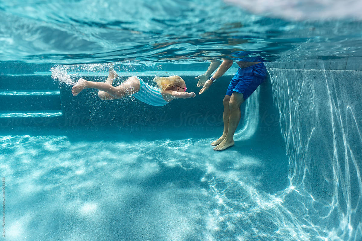 Girl swimming to dad\'s arms underwater