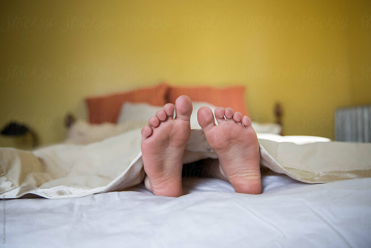 Feet of a child sticking out from the blankets of a bed