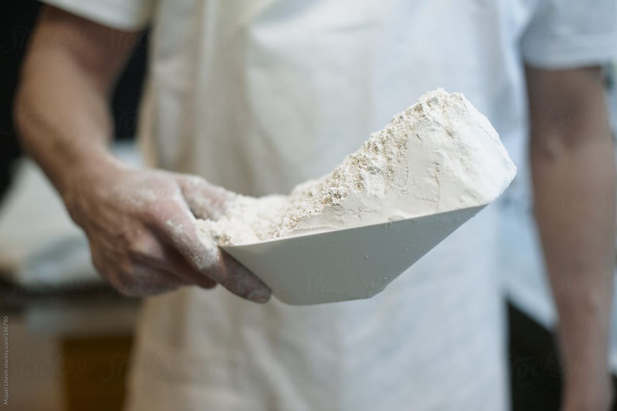 Baker hand holding a scoop of flour