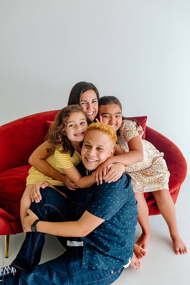 Two moms and daughters hugging on sofa