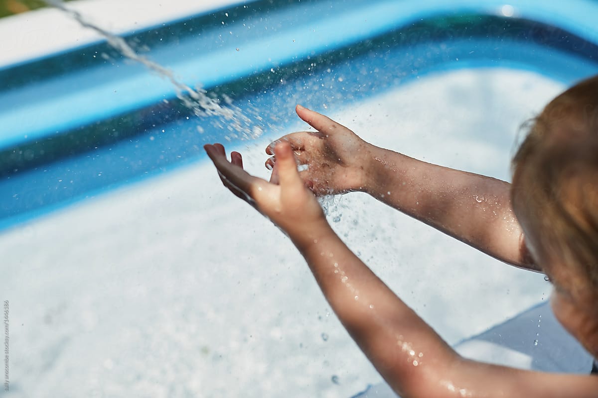 Child putting her hands in the water from the hose