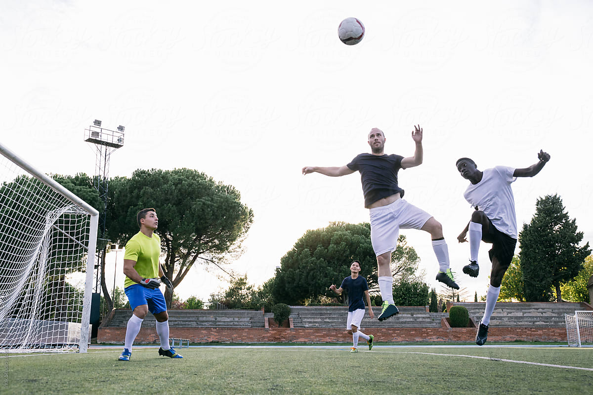 Multiracial football players making goal while shooting ball