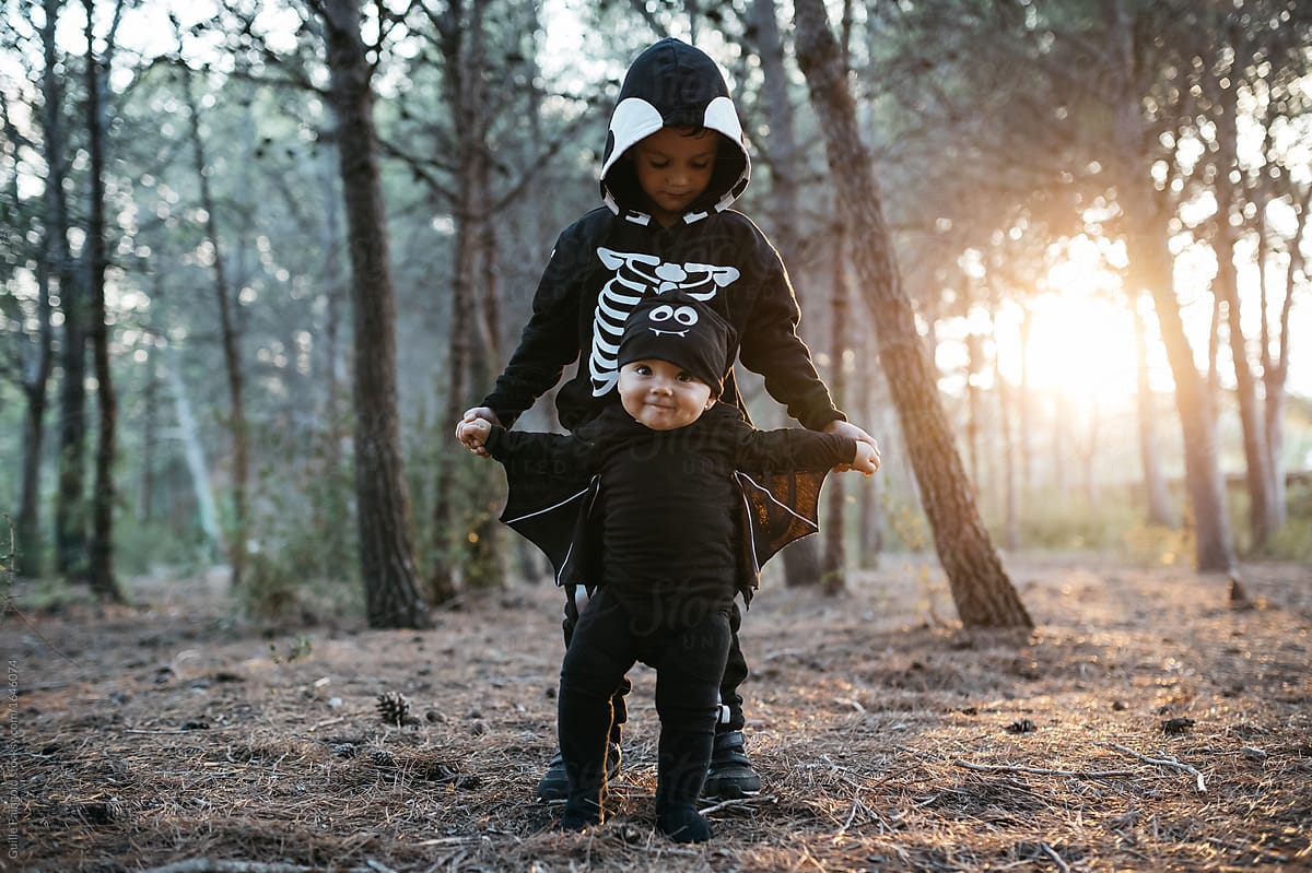 Brothers in halloween costumes in forest in evening.