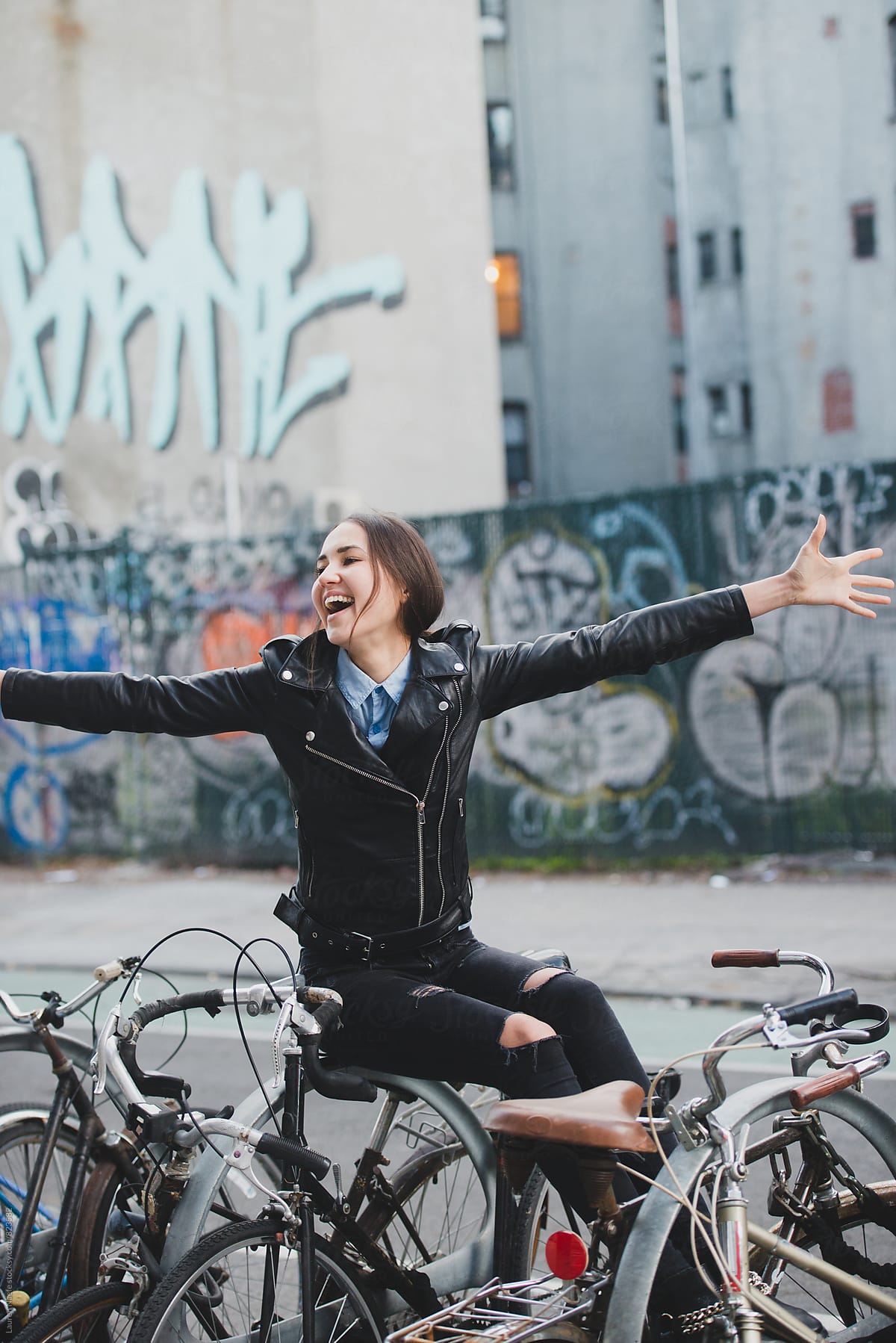 Free-spirited young woman sitting on bike rack