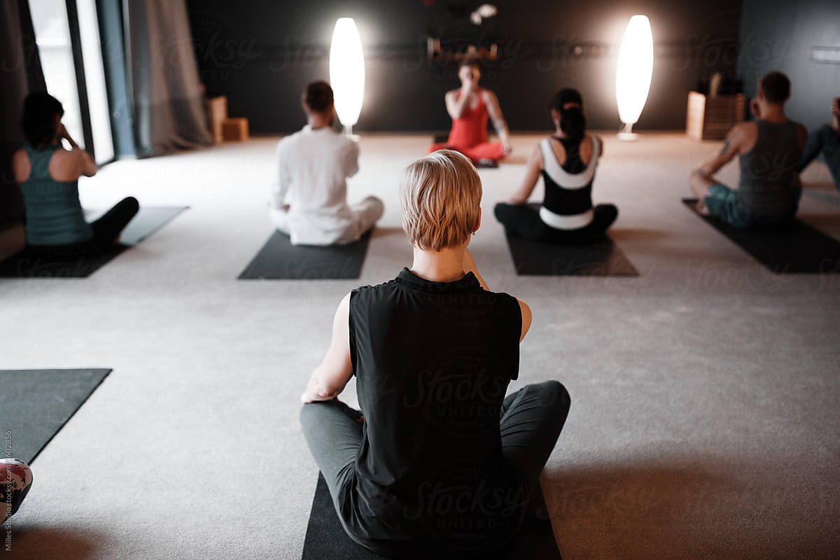 Anonymous man meditating with group in studio