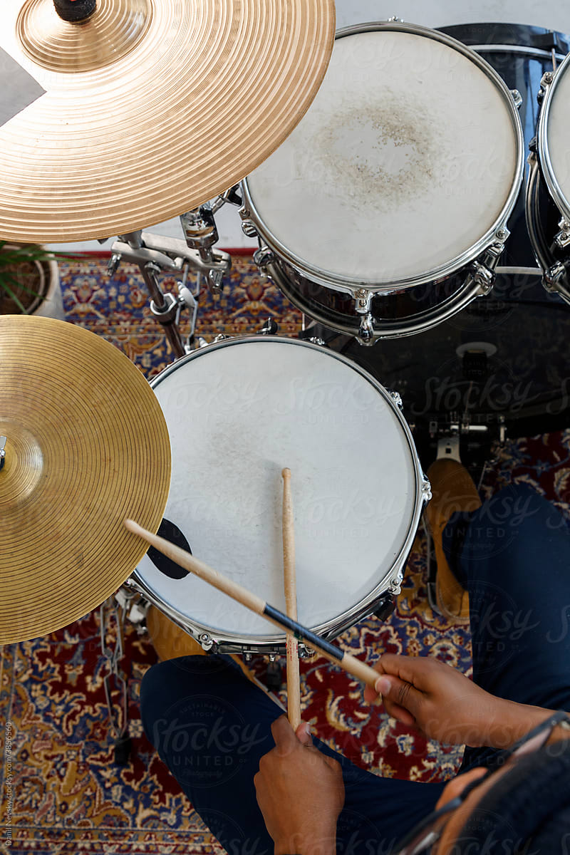 Crop black musician playing drums over ornamental carpet