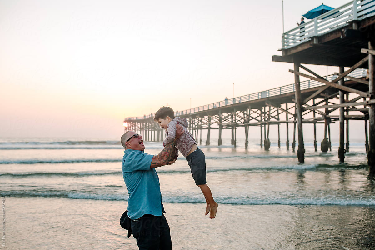 Happy dad lifts son high in air near pier