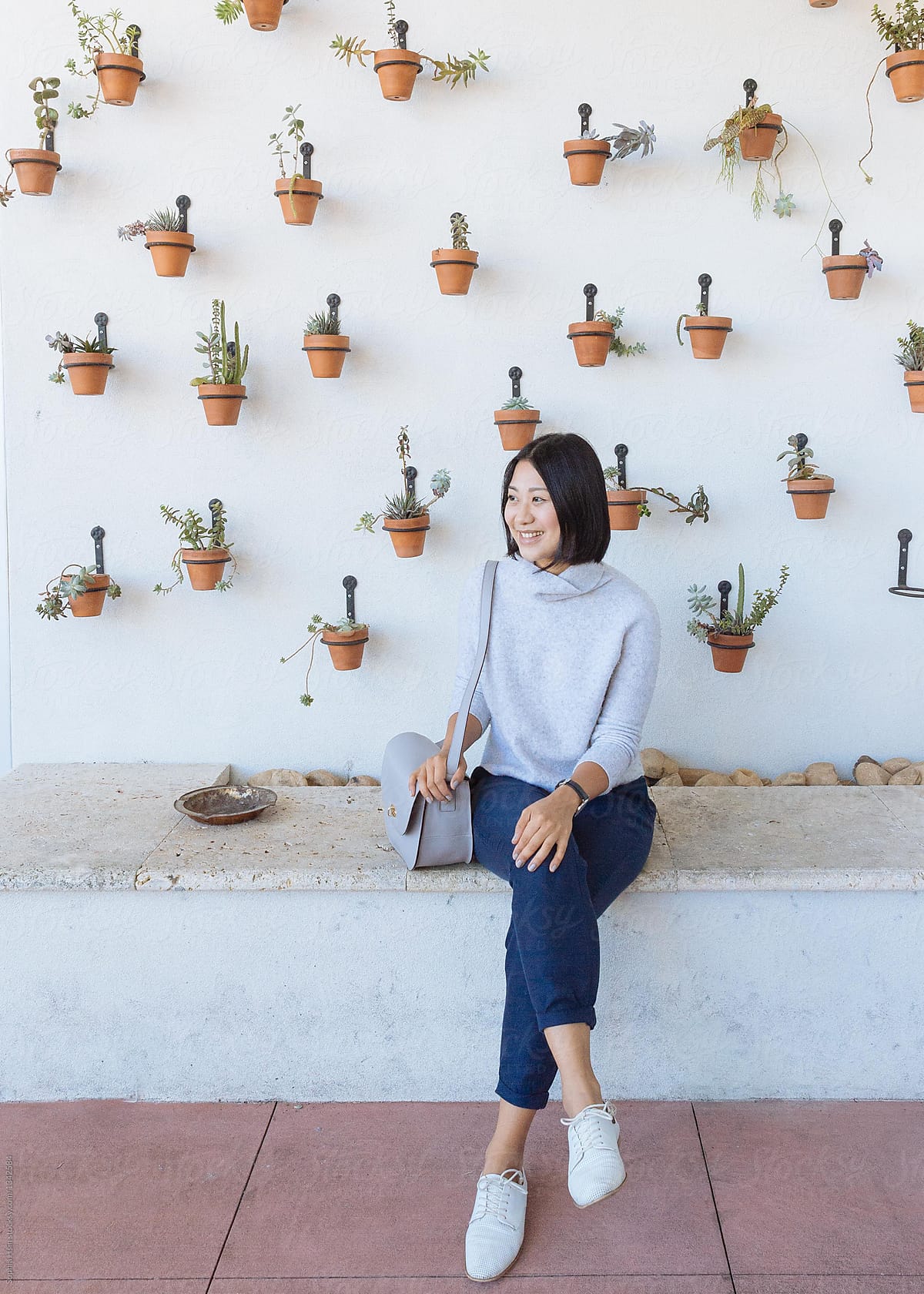 Girl sitting in front of white wall with plants