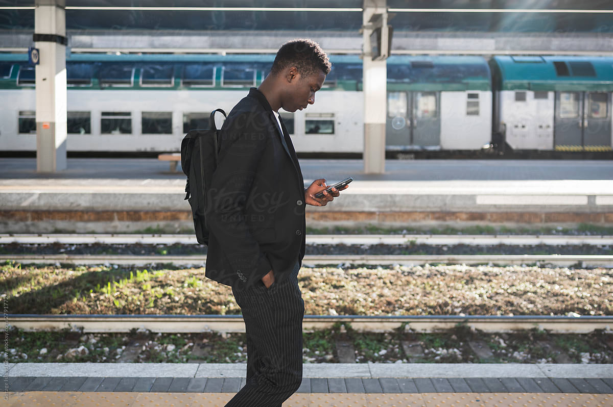 Young businessman using a mobile phone at train station