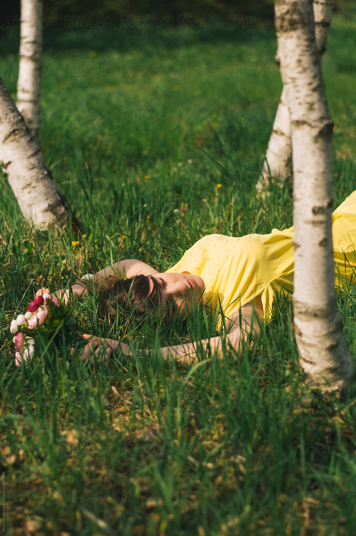 Woman In Yellow Dress Lying In The Grass By Stocksy Contributor