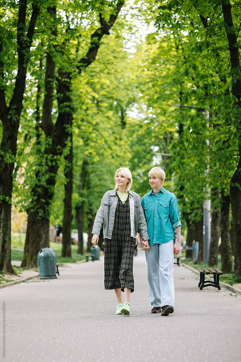 Girl with beloved person taking stroll among park zone in town