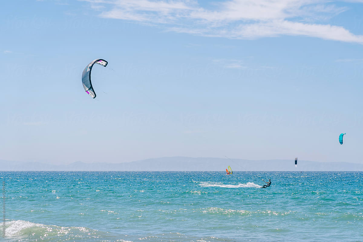 Surfer riding kiteboard on blue sea