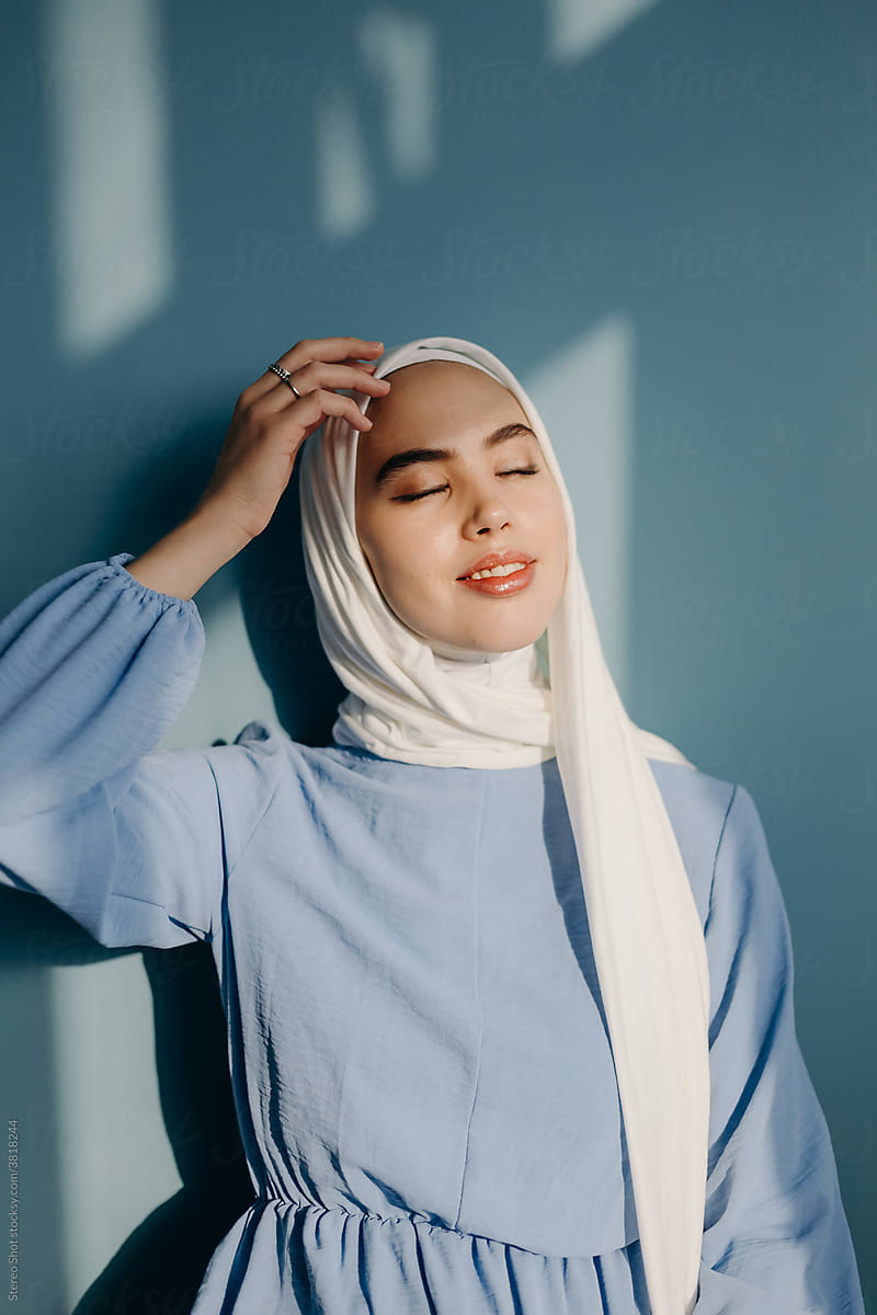 Tender Muslim woman adjusting hijab in studio