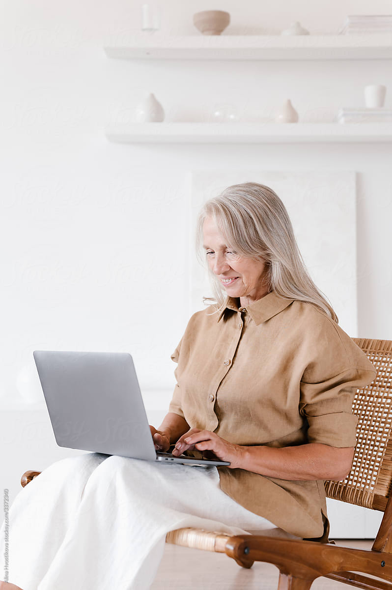 Happy senior woman using laptop on chair