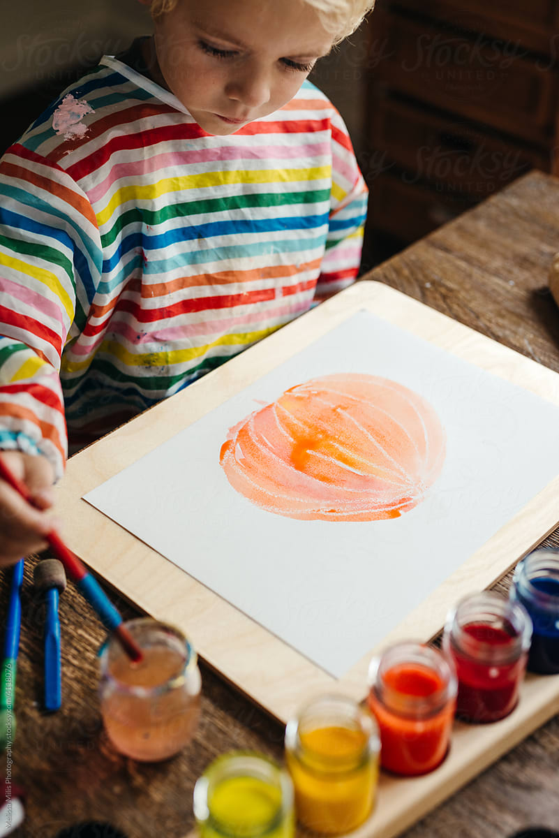 Kid painting on a printed paper with watercolour