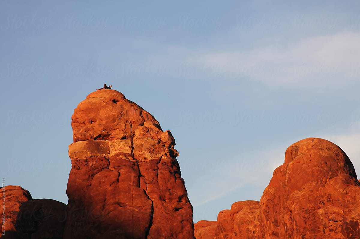 Anonymous mountain climber relaxing on top of one of Arches National Park\'s rock formations.