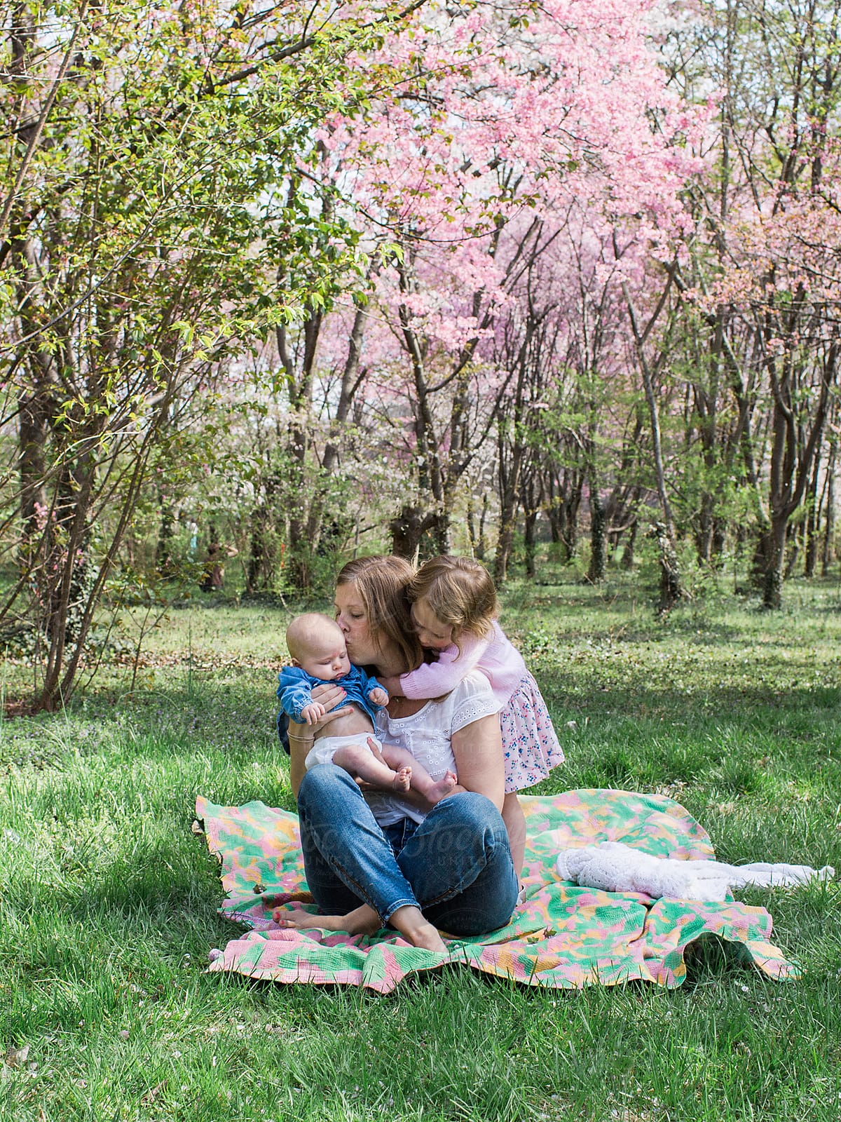 mother and children picnicking under spring blooms
