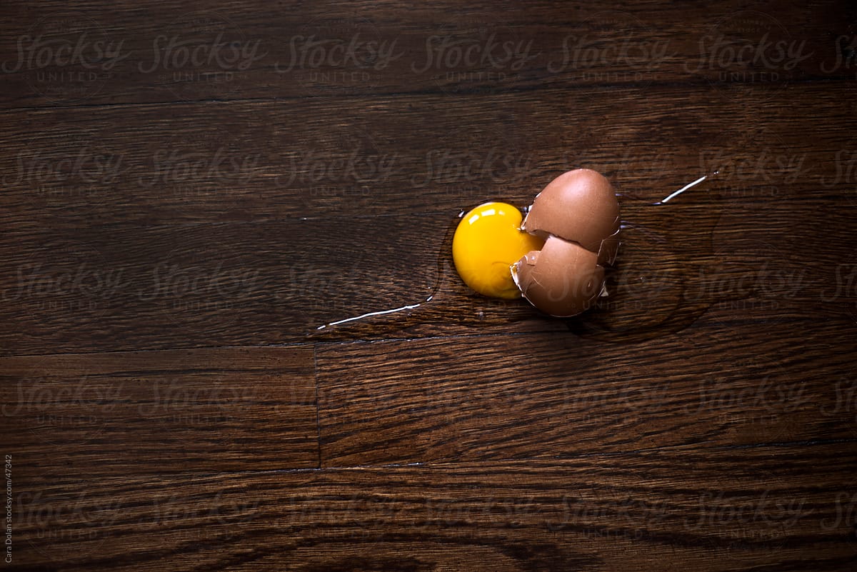 Broken egg that\'s been dropped on the kitchen floor