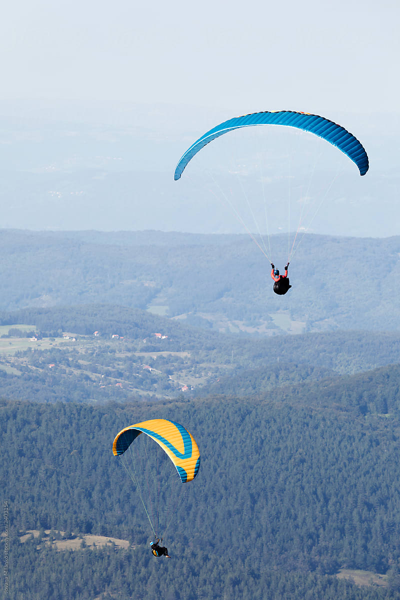 Two paragliders in the air over mountains