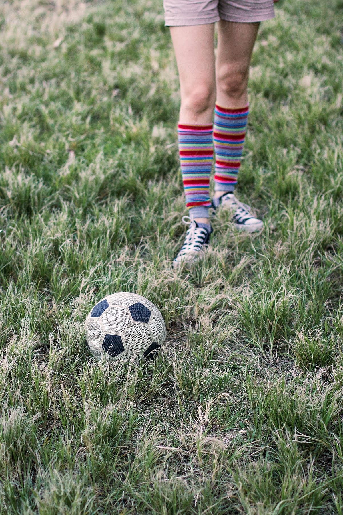 A pair of football kicking legs (with warmers) and feet on a grassy field