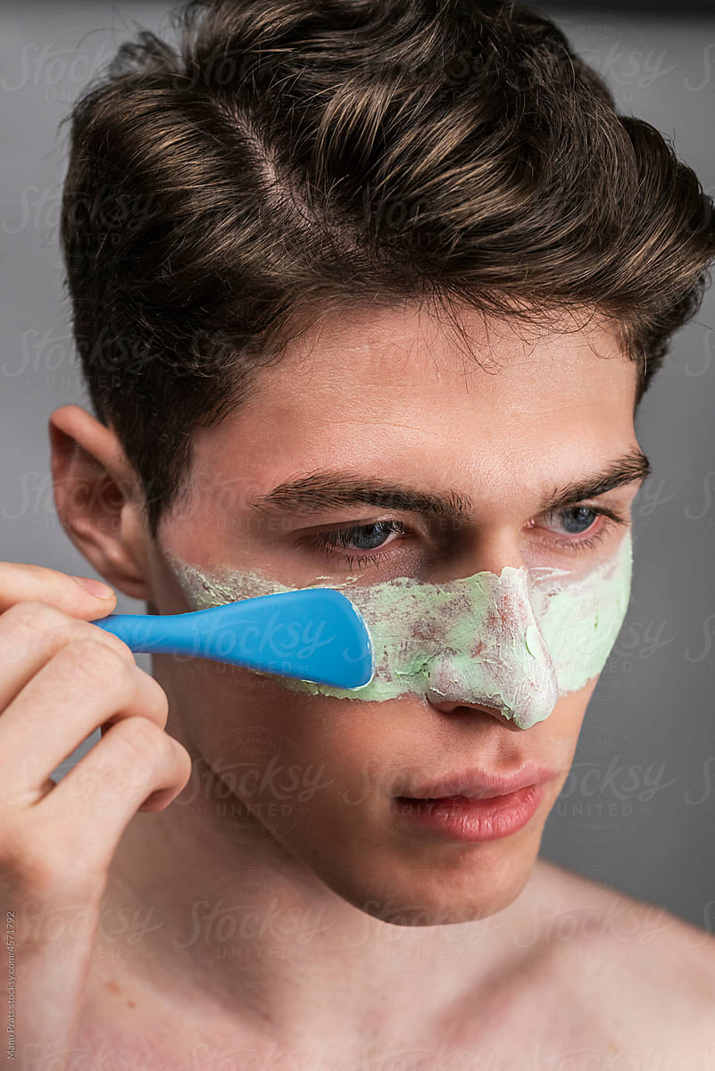 Modern man applying facial mask, male skincare