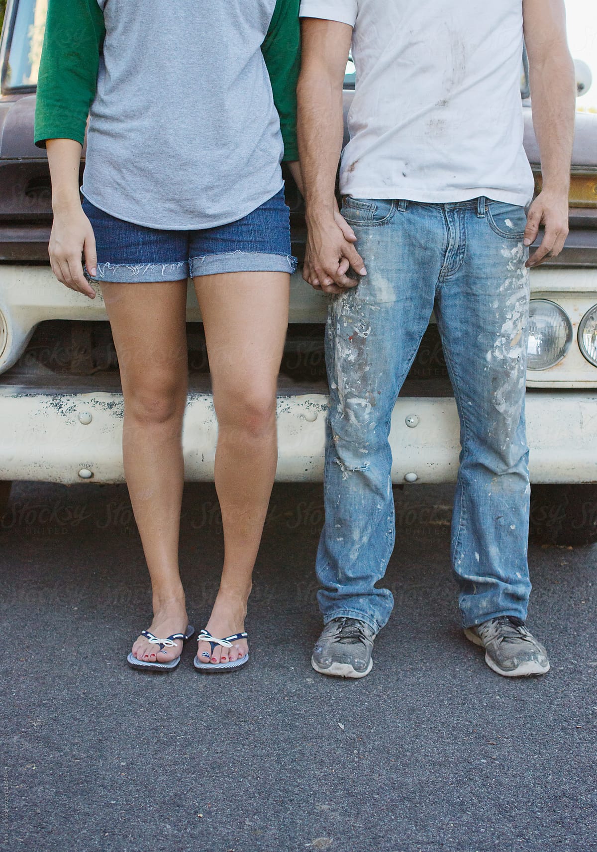 Young couple hold hands while standing in front of old pickup