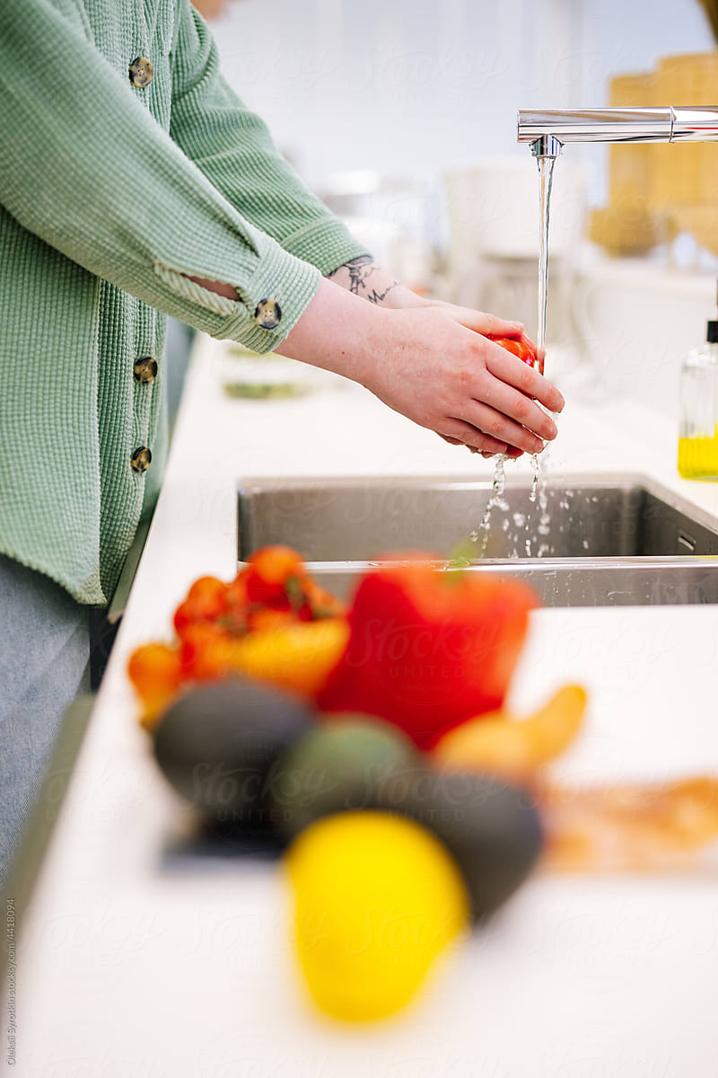 Person cleaning vegetables and fruits in kitchen