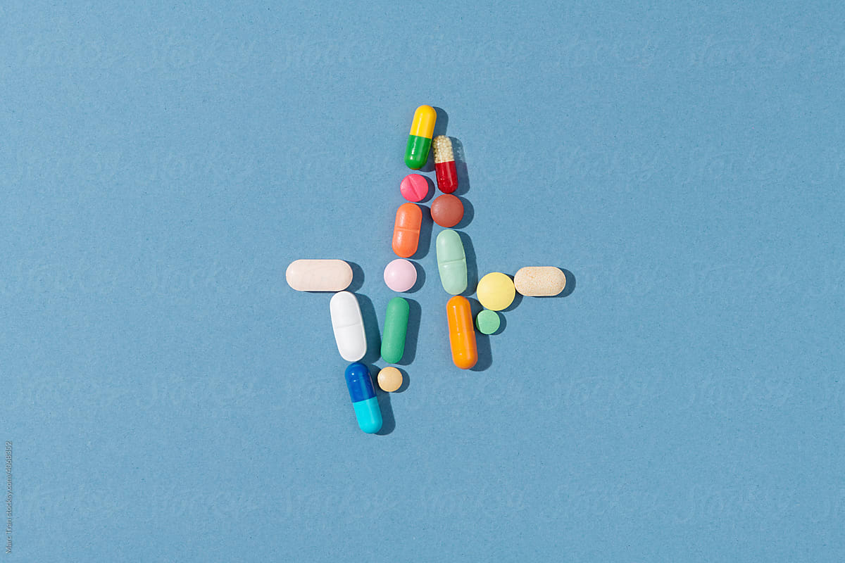 Multi-colored pills and capsules heap on a yellow background