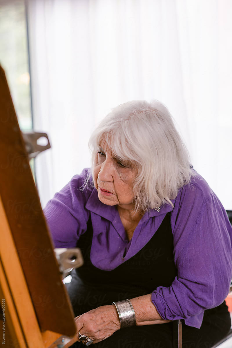 Artist elder woman painting at home