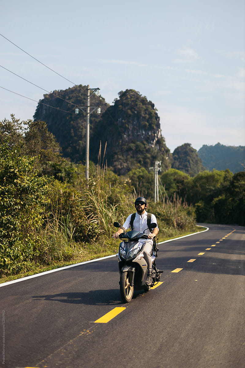Traveler driving a scooter in the nature of islands of Southeast Asia