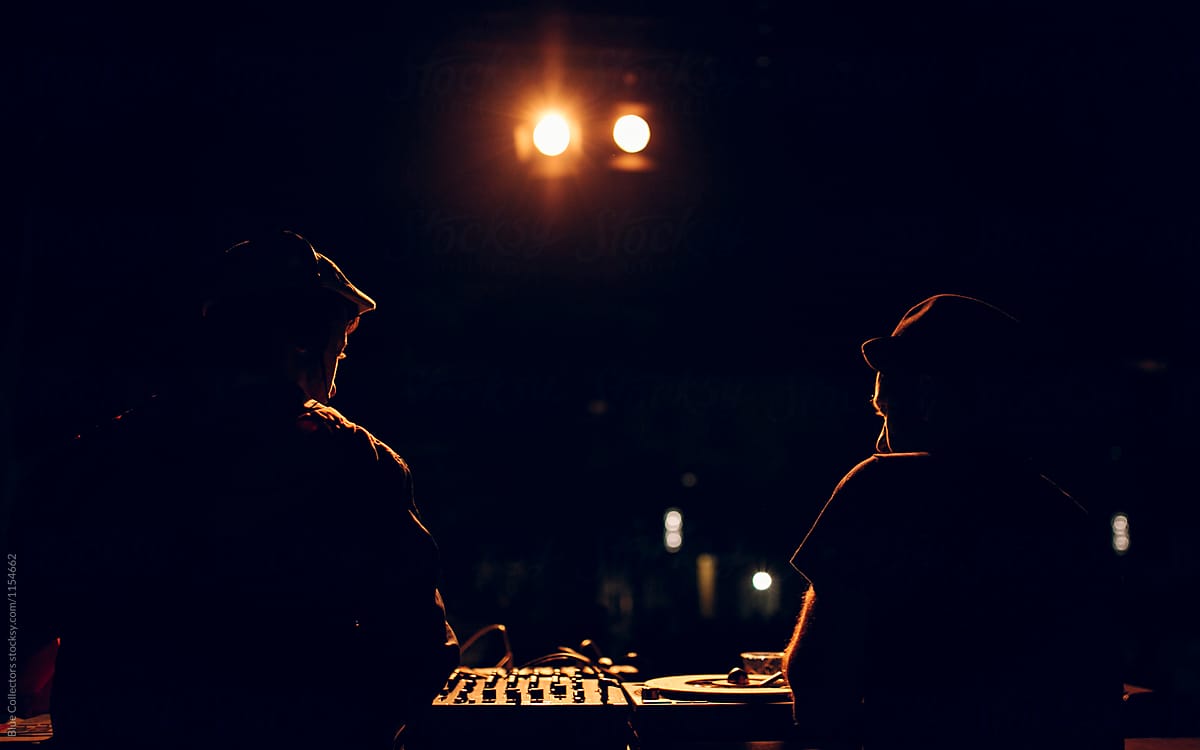 Two Dj playing the music in the night party, from behind
