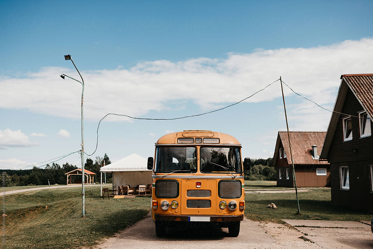 Old yellow school bus in a village in Latvia
