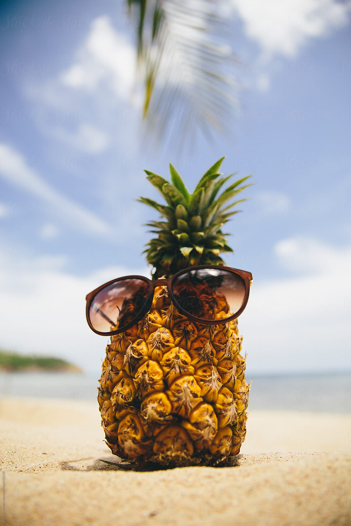 Pineapple dressed in sunglasses on the beach