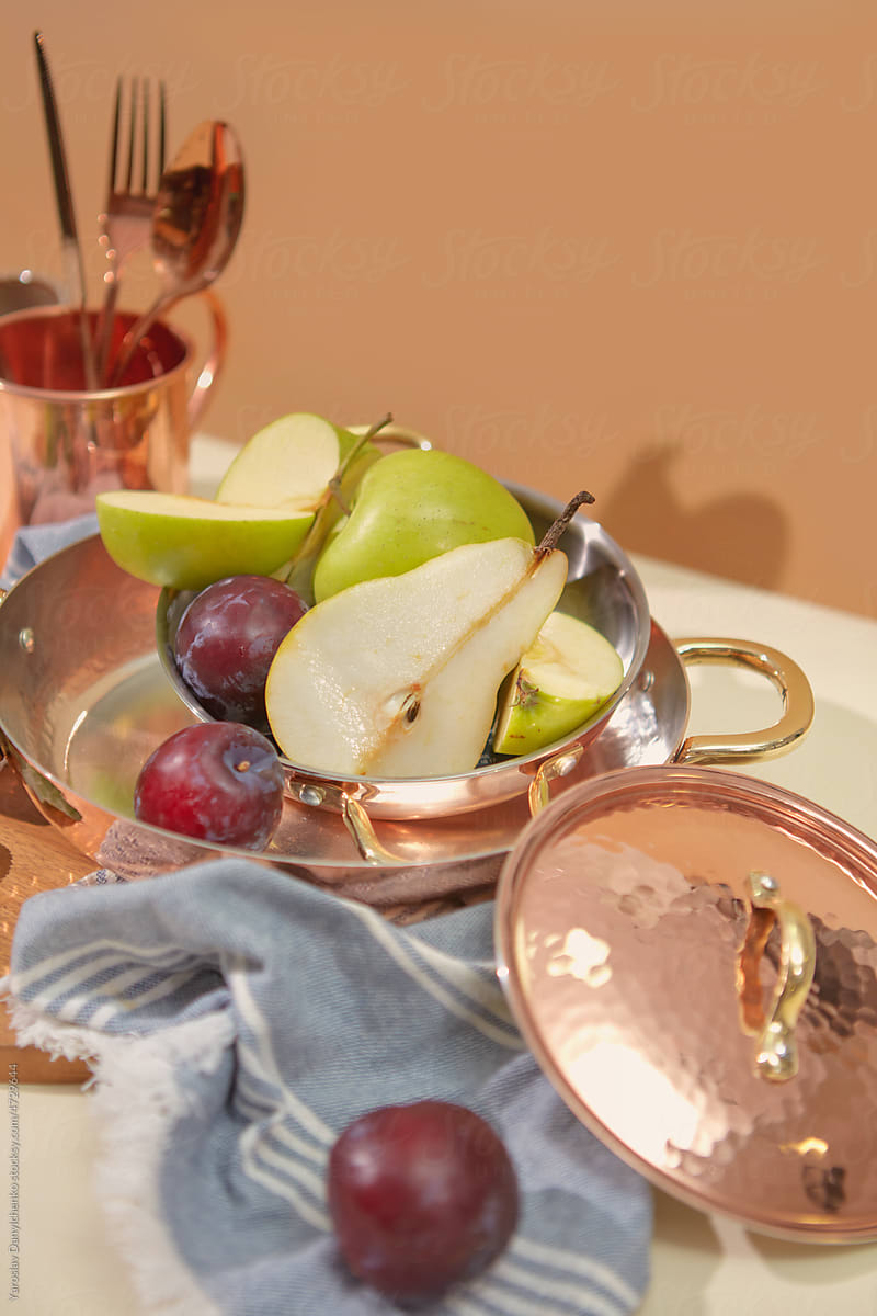 Copper dinnerware with fresh fruits in kitchen.