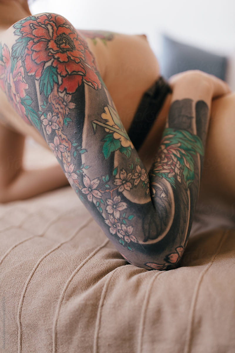 tattooed naked woman lying on the bed