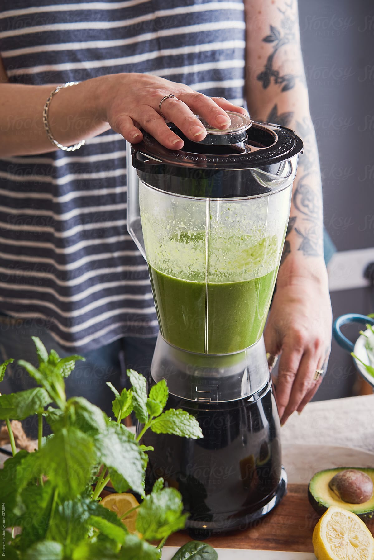 Woman using a blender to prepare a healthy detox smoothie drink.