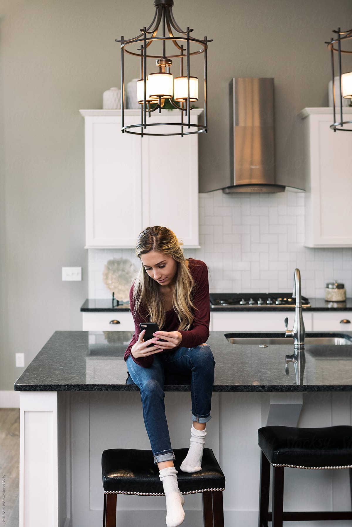 Home: Teen Sits On Counter Checking Email On Phone