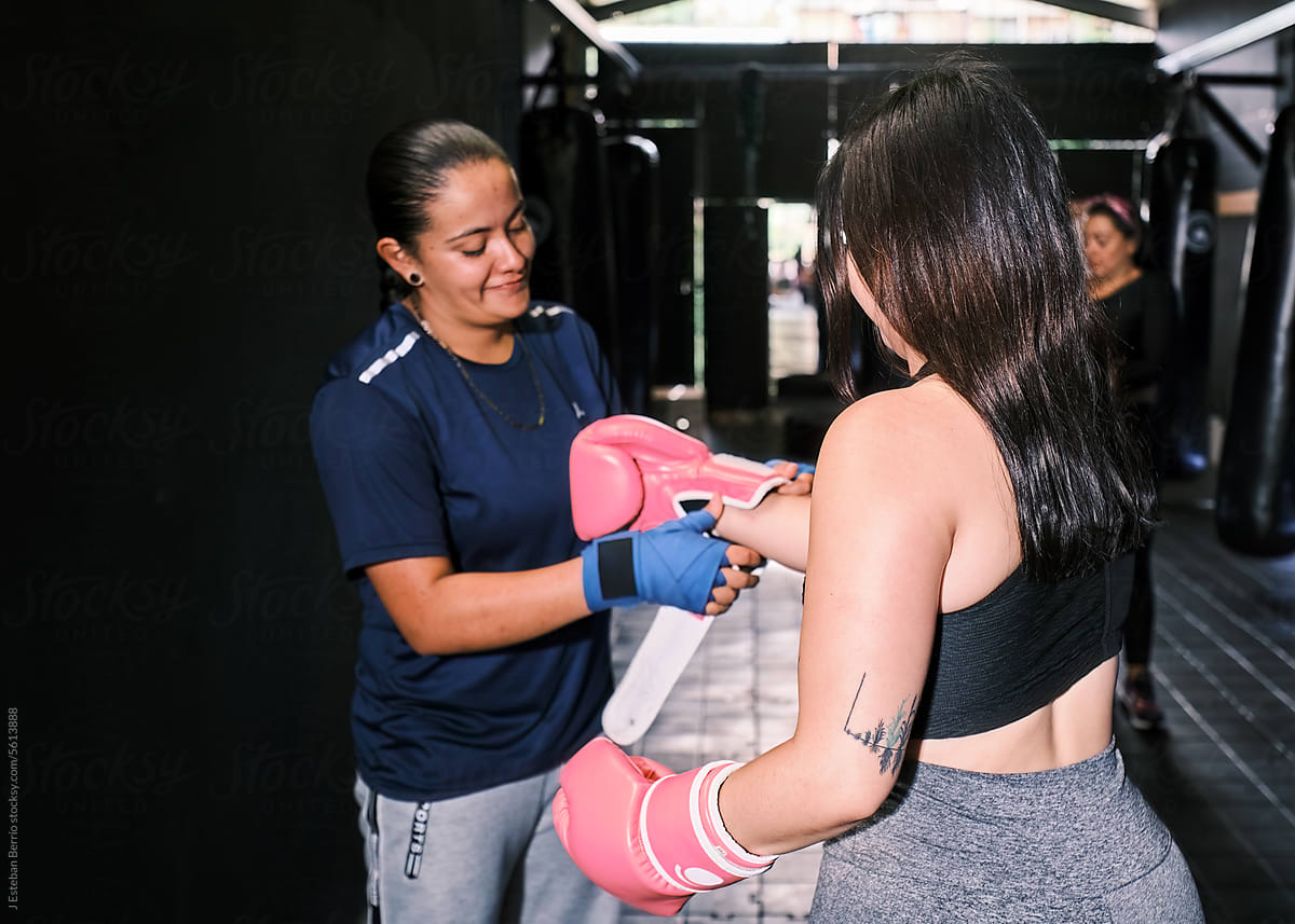 Woman putting boxing gloves on her training partner
