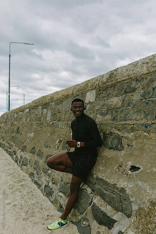 Young Runner Smiling Listening Music with his Mobile Phone