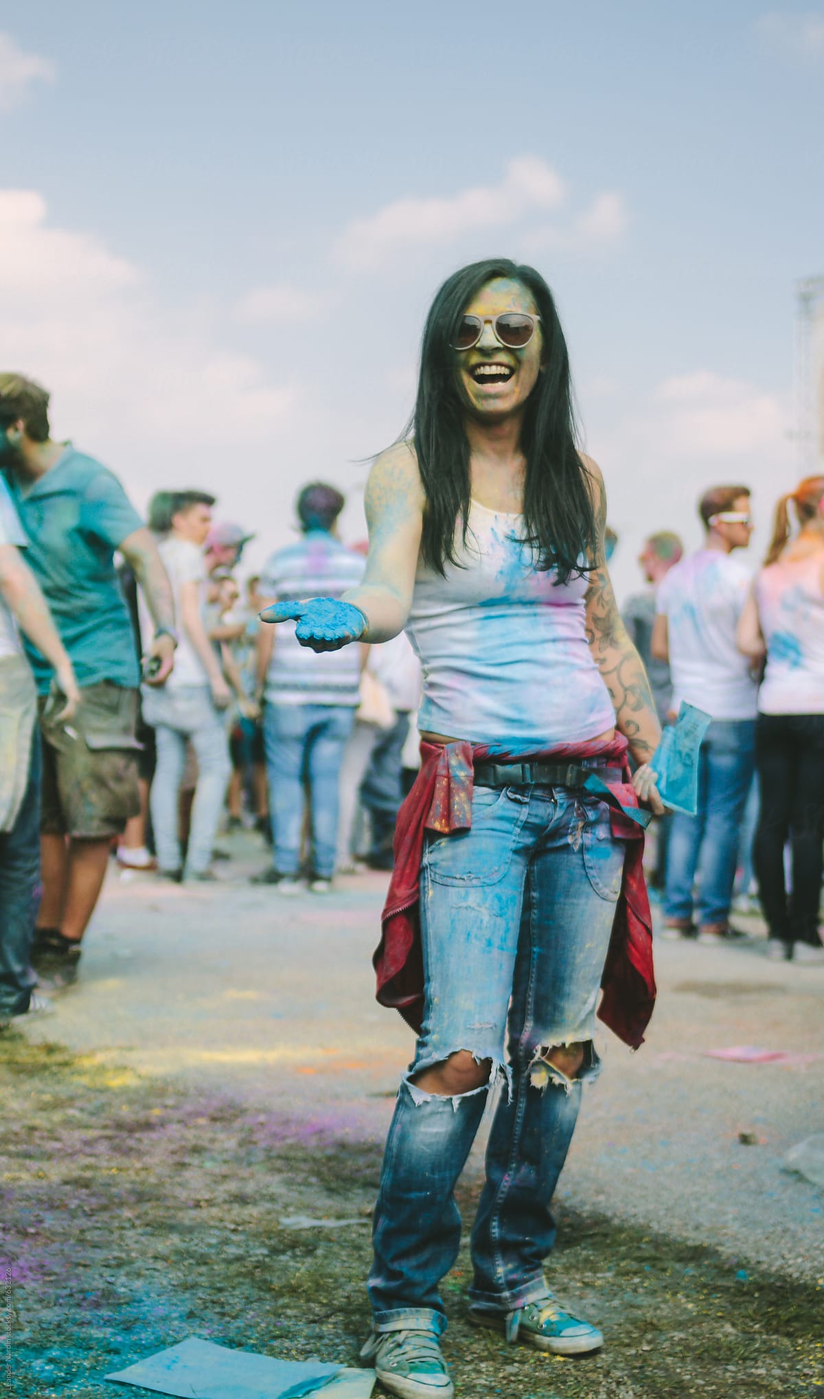 dirty colorful painted young woman laughing on an outdoor music festival