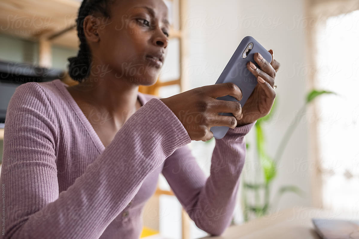 Black woman browsing mobile in home office