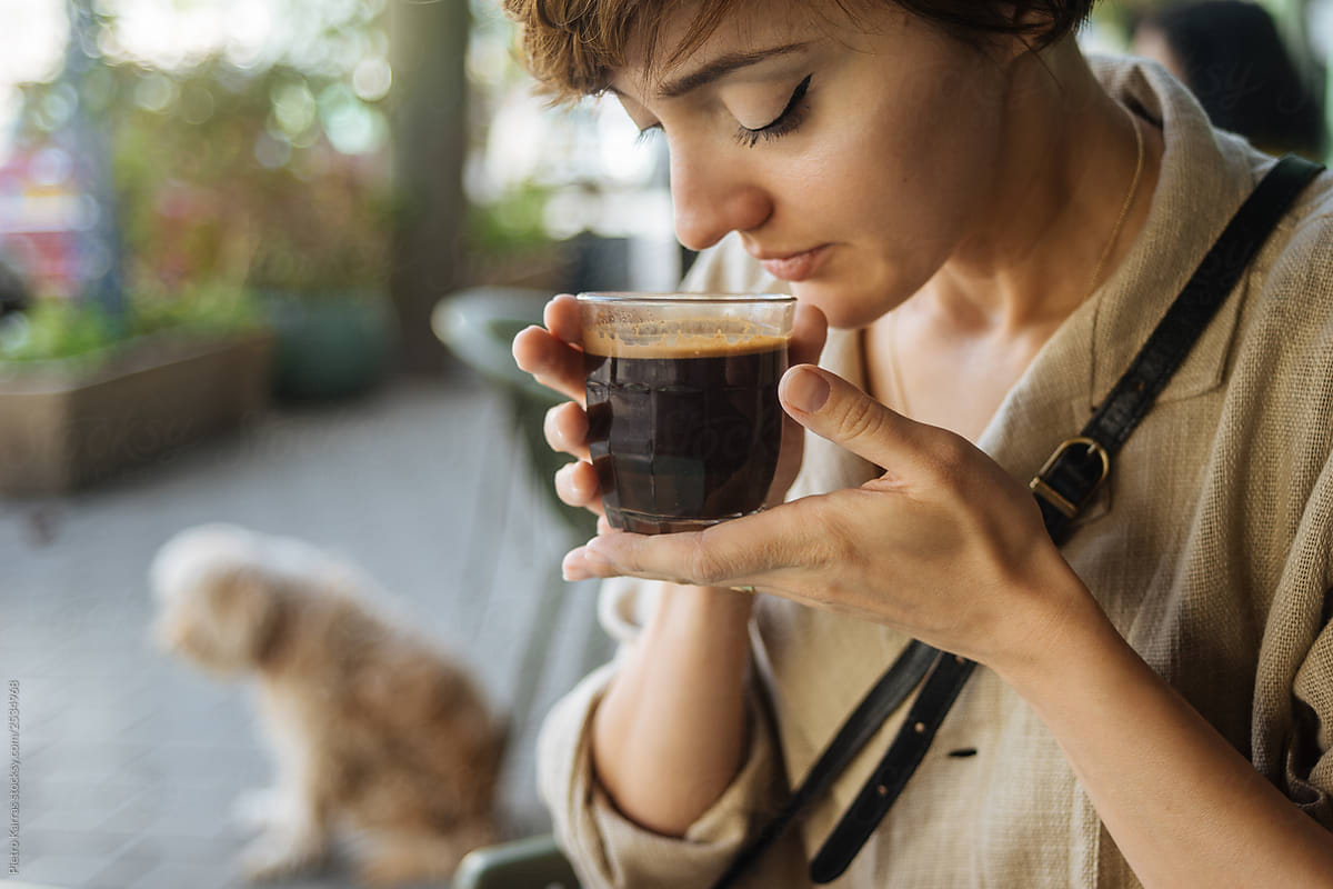 Woman with cup of coffee on street near dog